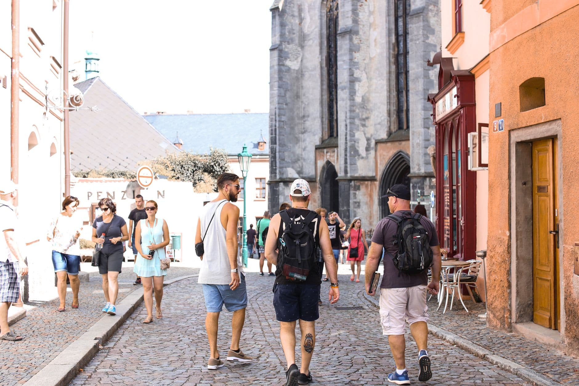 A bustling stone road in a historic European city filled with tourists enjoying a summer day.