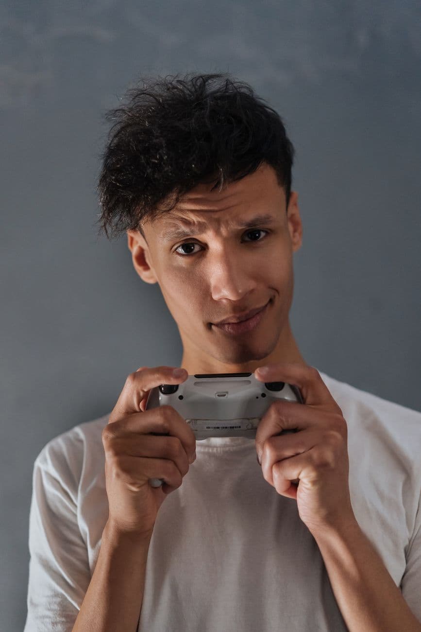 Portrait of a young man holding a game controller with a focused expression indoors.