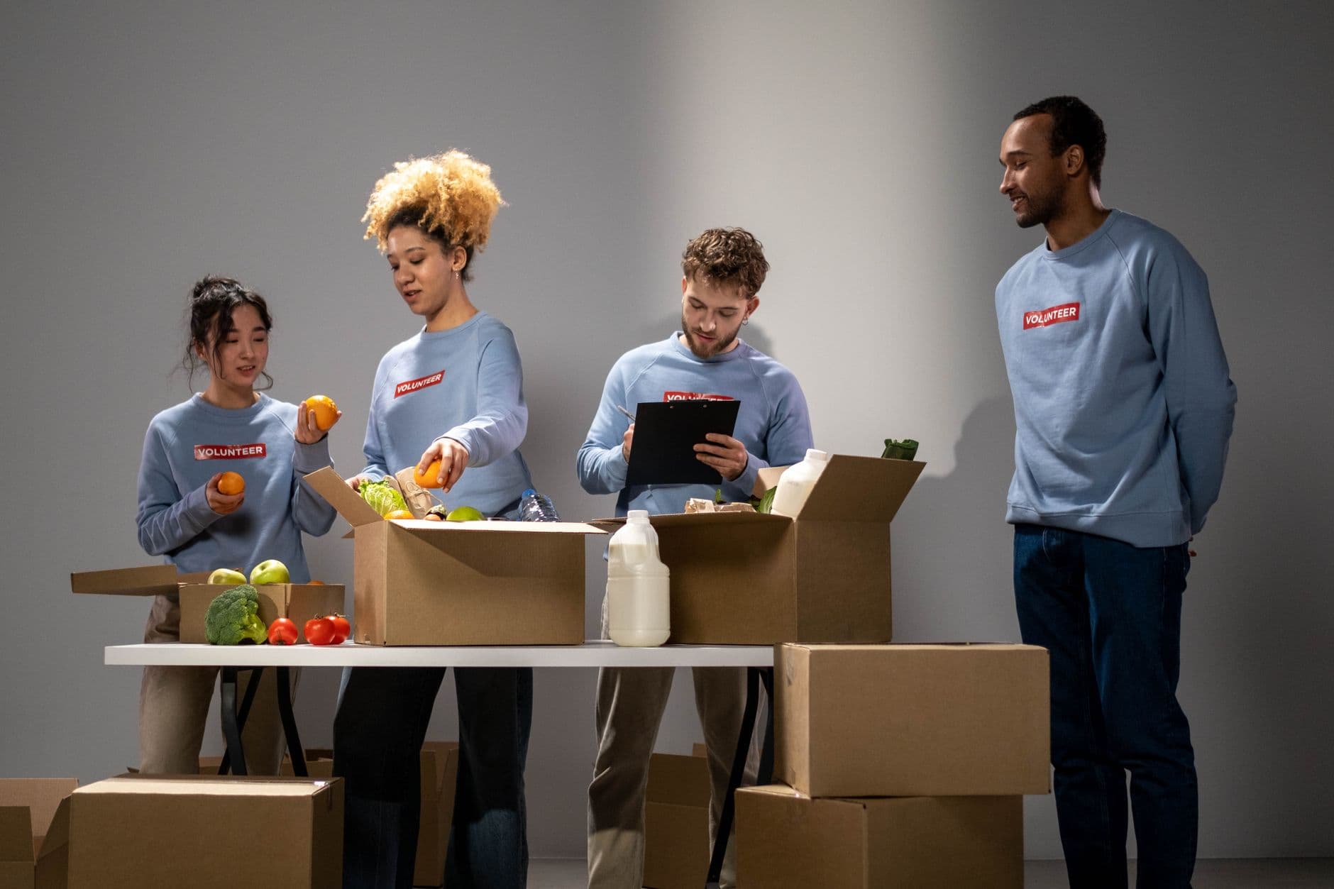 A diverse group of volunteers organizing and packing food donations at an indoor facility.