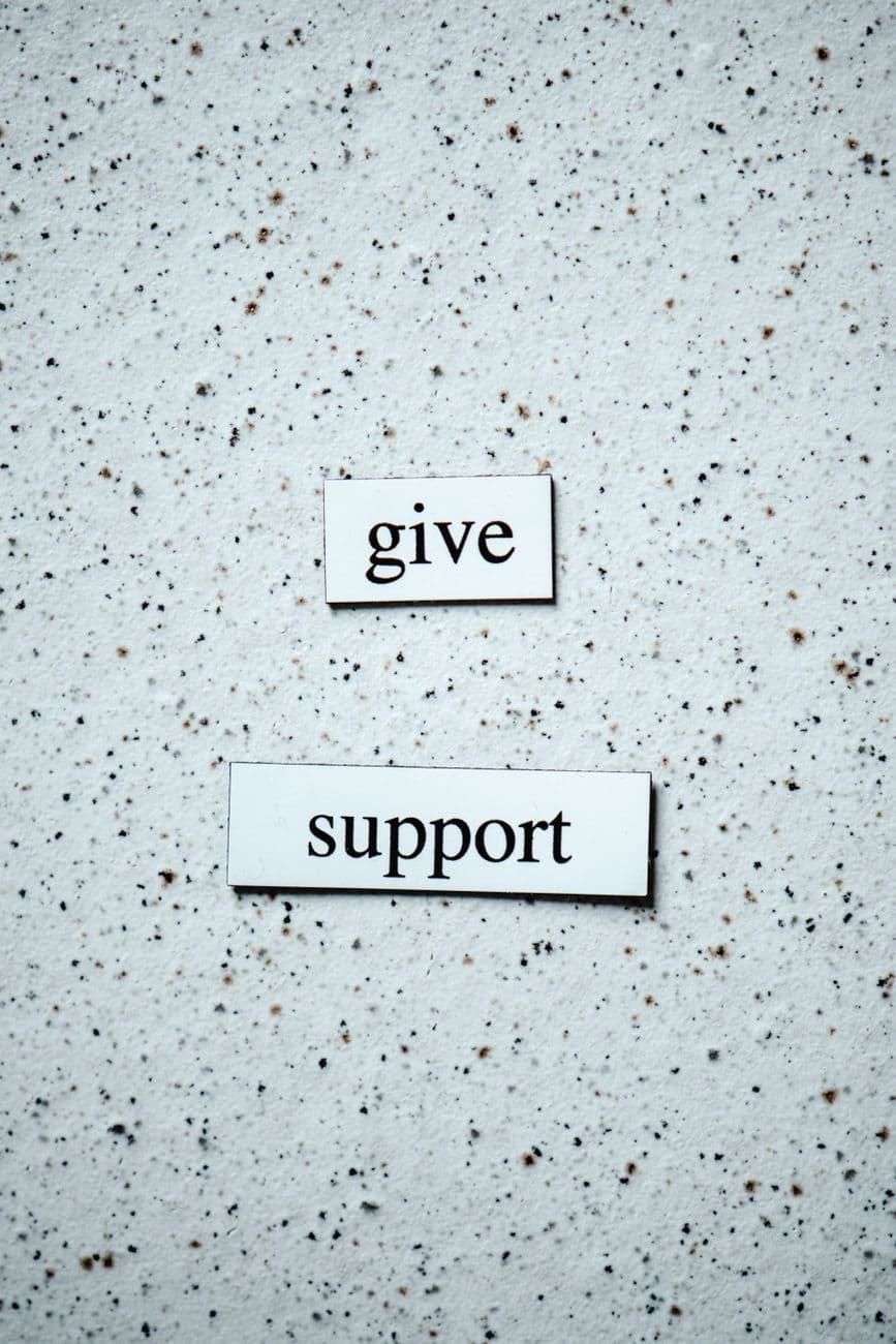Text saying 'give support' on a textured surface, promoting encouragement.