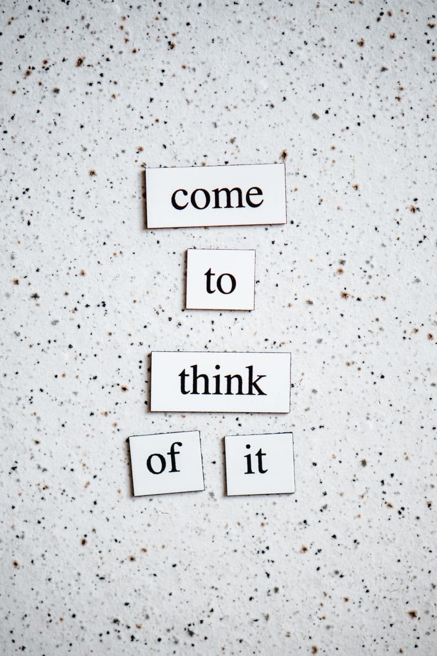 Motivational words 'come to think of it' on a speckled white background to inspire reflection.
