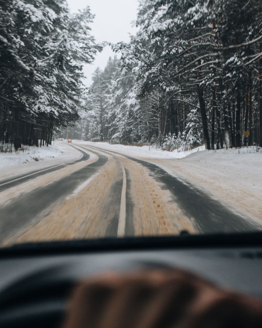 Capturing a serene winter drive through a snow-covered forest road.